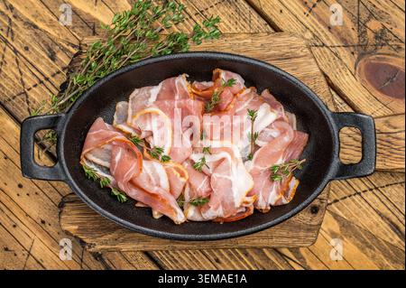 Uncooked bacon strips arranged with thyme on wooden board great for kitchen cooking advertising recipe blogs and menu design Stock Photo