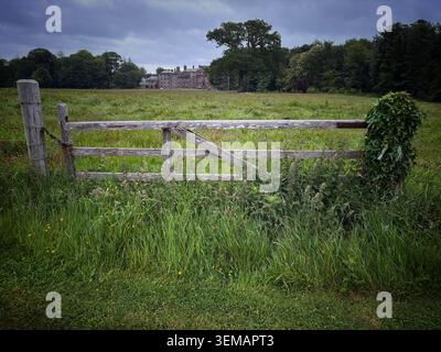 Country estate, old wooden gate with grass field and large country home in the background - photo in UK in 2026 Stock Photo