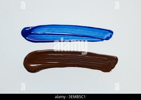 Brown and blue acrylic paint brushstrokes on a white background with visible texture and smooth brush marks Stock Photo