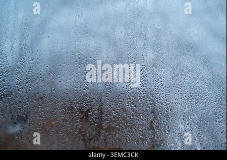 Condensation on glass with tiny water droplets, creating a blurred surface. Soft colors and misty ambiance, ideal for autumn or cold weather settings. Stock Photo