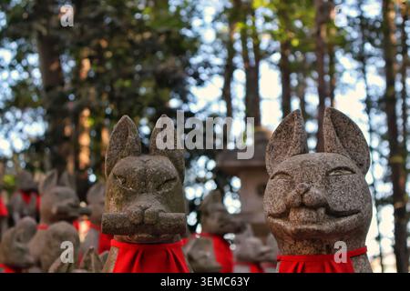 Low angle view of two expressive stone Kitsune statues looking towards the sky. Stock Photo