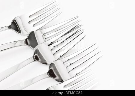 Metal forks arranged on white background. Kitchen utensil collection and dining equipment concept with clean presentation. Stock Photo