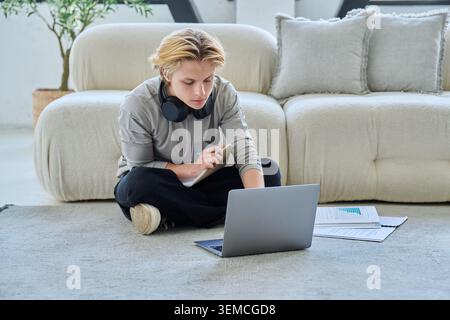 Young student studying with laptop on floor at home Stock Photo