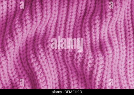 Close up, macro of crumpled pink knitted fabric with visible wrinkles, folds and soft waves. Soft wool texture with detailed stitches and creases, nat Stock Photo