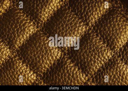 Close up, macro of yellow quilted leather texture with stitched diamond pattern, luxury material surface shining metal effect for fashion, upholstery Stock Photo