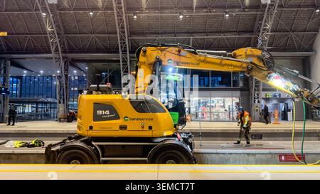 A yellow Baneservice Liebherr 914 Compact road-rail excavator performing maintenance work on tracks at Oslo S  train station in Norway at night Stock Photo