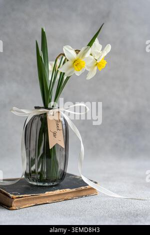 Bouquet of fresh white daffodil flowers on old book Stock Photo