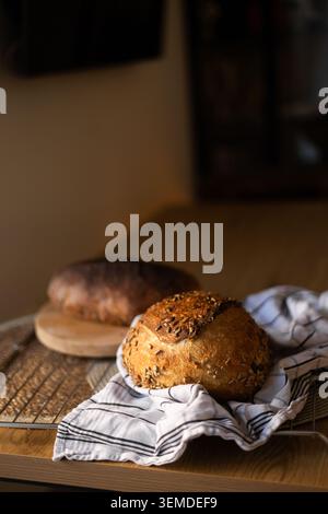 Fresh homemade sourdough bread baked with Lievito Madre, resting on a cooling rack with a linen towel in warm natural light, rustic kitchen scene and Stock Photo