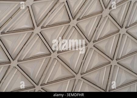 Abstract view of a geometric ceiling with repeating triangular panels and beams, showcasing modern Uzbekistan architecture design and structural symme Stock Photo
