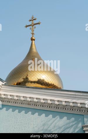 Close-up of a golden church dome topped with an ornate cross against a clear blue sky, showcasing religious architecture in Uzbekistan, Central Asia, Stock Photo