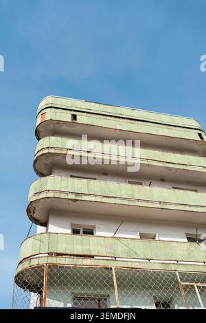 Low angle view of a modernist apartment building in Uzbekistan, featuring curved balconies, pale green panels, and weathered details against a clear b Stock Photo