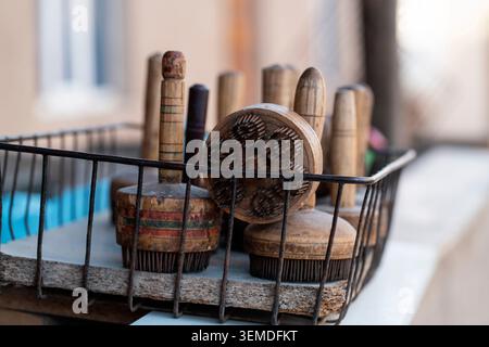 Close-up of traditional Uzbek kitchen brushes and handmade wooden tools resting in a metal basket on a rustic shelf, highlighting everyday food prepar Stock Photo