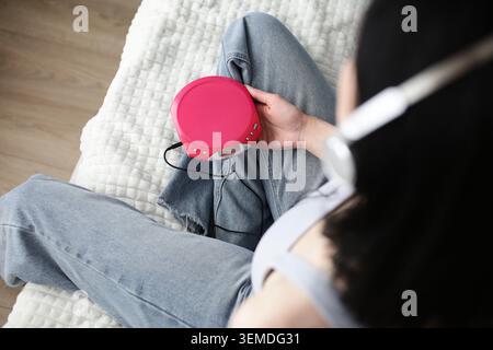 Overhead view of a person holding a portable CD player while wearing headphones, capturing Y2K aesthetic and retro audio gear for analog media revival Stock Photo