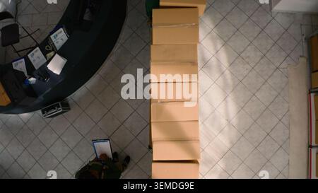 Top down view of warehouse chief supply chain officer examining cardboard box parcels in parallel, comparing findings. Depository staff members making sure stocks and inventory are well organized Stock Photo
