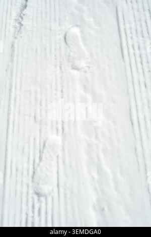 Footprints are visible on the surface of the snow, showing a path in a winter landscape. The snow is untouched except for the steps, indicating recent Stock Photo