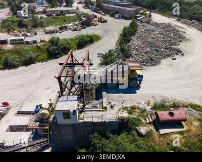 Heavy machinery works at a granite quarry site. Trucks are transporting stone materials. Workers are managing the operations at the site while machine Stock Photo