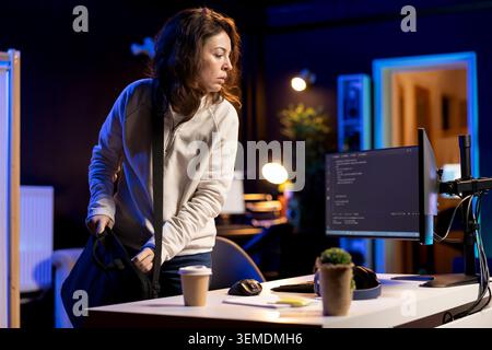 System administrator arriving in office, ready to design and develop software applications on laptop. IT expert starting job shift, unpacking notebook, implementing and maintaining company systems Stock Photo