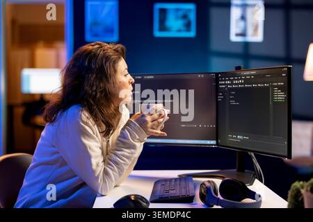 Programmer drinking cup of coffee in the morning, securing company servers from virus attacks. IT remote employee enjoying hot beverage while building firewalls protecting data Stock Photo