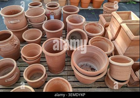 A garden center displays many empty terracotta pots and planters in different sizes and shapes on a wooden pallet for customers to choose from during Stock Photo