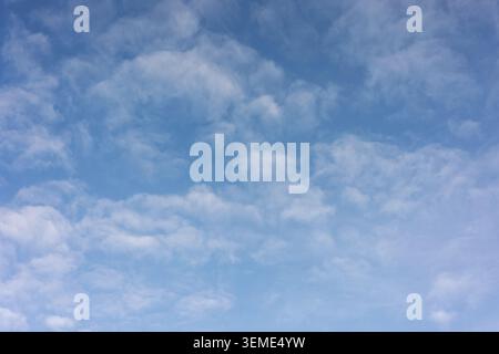 Broken cloud formations drifting across a bright blue summer sky Stock Photo