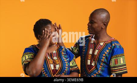 Husband comforting wife with painful headache on camera, dealing with stress and tension. Young man trying to help woman who feels unwell and sick, person rubbing temples to ease migraine pain. Stock Photo