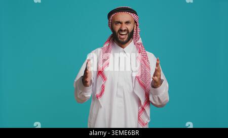 Confident man cheering and presenting his support in front of camera, feeling optimistic and happy about something. Middle eastern guy being brave and strengthening forces with cheers. Stock Photo