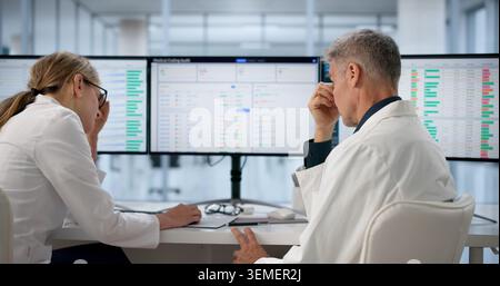 Hospital Administrator Reviews Spreadsheets On Computer, Feeling Tired And Stressed. Stock Photo