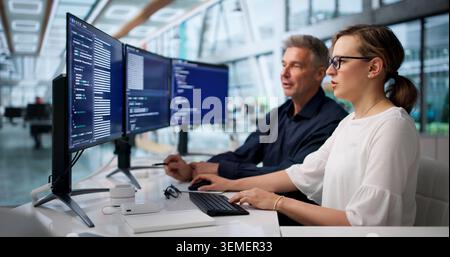 Two Software Engineers Coding Secure Systems Together In Modern Office. Stock Photo
