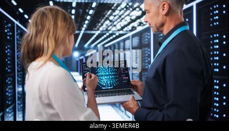 Two Data Scientists Use Laptops Discussing AI Model Development In Tech Center. Stock Photo