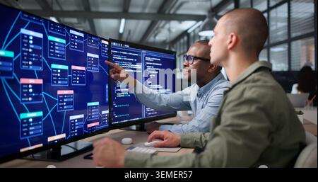 Two Young Software Developers Collaborate Using Visual Workflow Editor On Computer. Stock Photo