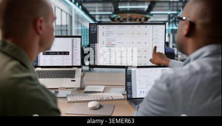 Two Risk Analysts Working Together On Detailed Financial Report Using Laptops. Stock Photo
