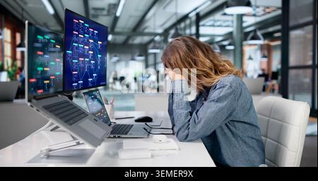 Woman Feeling Tired And Stressed While Using Low Code Platform On Laptop. Stock Photo