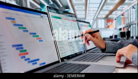 Woman Updates Agile Task Board Using Laptop In Modern Office Workspace. Stock Photo