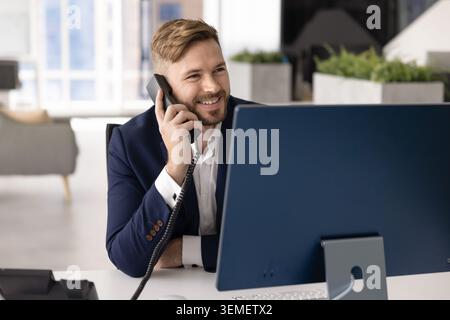 Smiling businessman in suit talking on landline phone Stock Photo