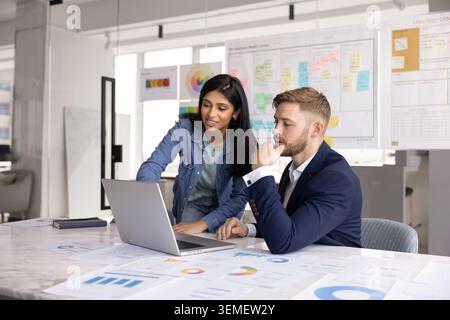 Young 30s Indian woman showing to colleague presentation on laptop Stock Photo