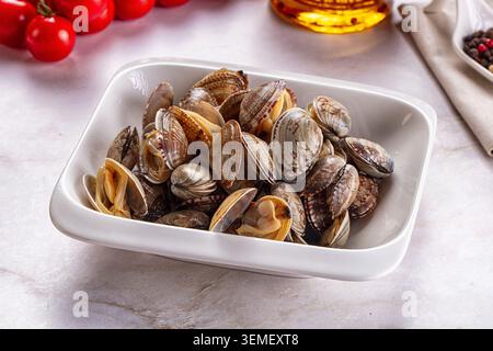 Fresh steamed clams served in a white ceramic rectangular dish on a light marble background Stock Photo