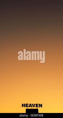 Minimalist conceptual image featuring a Heaven sign silhouetted against a warm golden sunset sky. Clean composition with extensive copy space symboliz Stock Photo