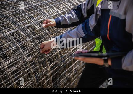 Close up hand of builders inspecting steel wire mesh construction site, Two workers examine large metal wire mesh, checking to large metal wire mesh s Stock Photo