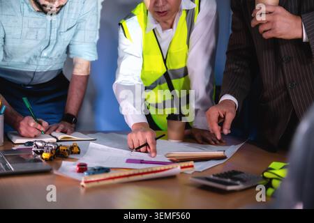 Close up hands engineers drawing blueprint construction planning boardroom night, Three workers examine a blueprint together, Three individuals collab Stock Photo