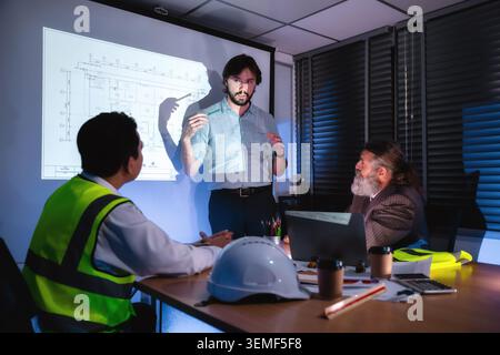 Engineering team discussing construction plan in dark meeting room, Construction manager explaining infrastructure plan with senior manager brainstorm Stock Photo