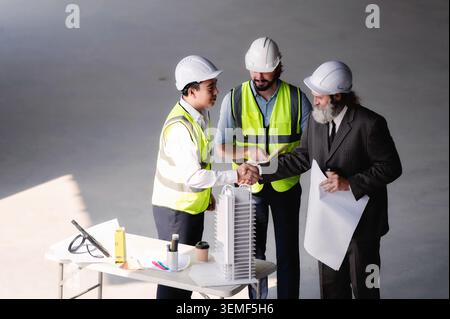 Senior businessman with architect shaking hands with young engineer at empty space floor in building construction site, real estate investors construc Stock Photo