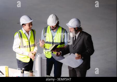 Real estate developers examining architectural model at empty space floor in building construction site, High angle view close up site managers enjoy Stock Photo