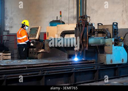 Industrial factory worker operating automated laser metal cutter machine, engineer technician control panel automated laser metal cutter machine heavy Stock Photo