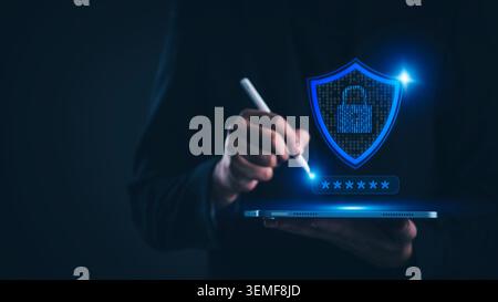 Businessman using tablet with cybersecurity shield and padlock icon. Data protection, network security, and user privacy concept. Secure login access Stock Photo