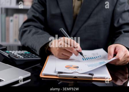 Close up businessman hand analyzing financial report data with calculator. Professional accountant working on investment strategy, corporate tax, mark Stock Photo