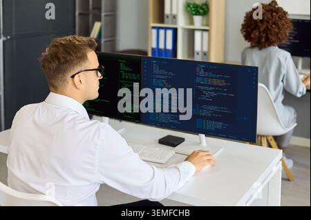 Programmer coding on wide monitor in office, focused software workflow engineering Stock Photo