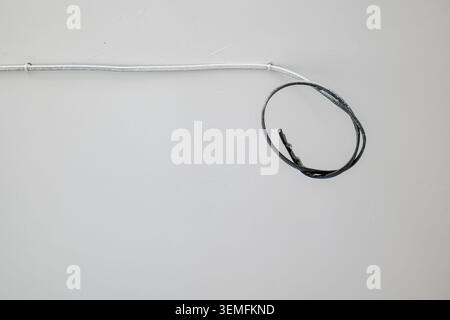 White and black electrical wires on a white wall Stock Photo