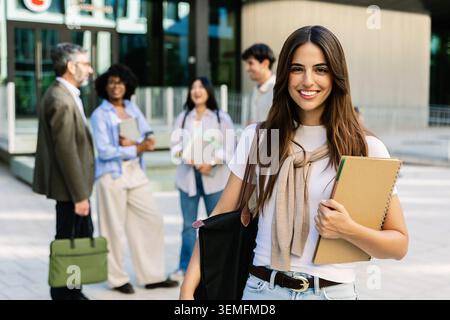 Portrait of young adult university female student holding notebook on campus Stock Photo