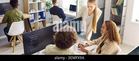 Diverse developers collaborating on code in a startup office during team meeting Stock Photo