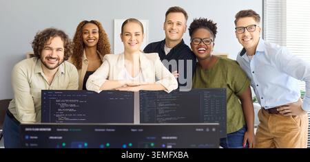 Happy software developers team portrait in startup office behind coding monitors Stock Photo